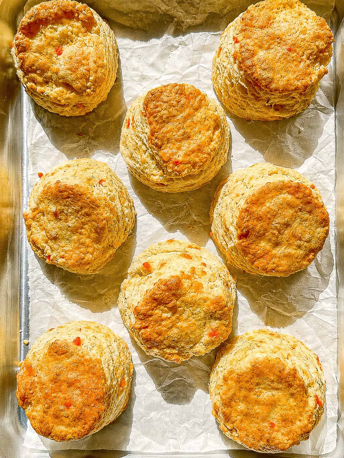 Pimento cheese biscuits on a parchment paper covered sheet pan.