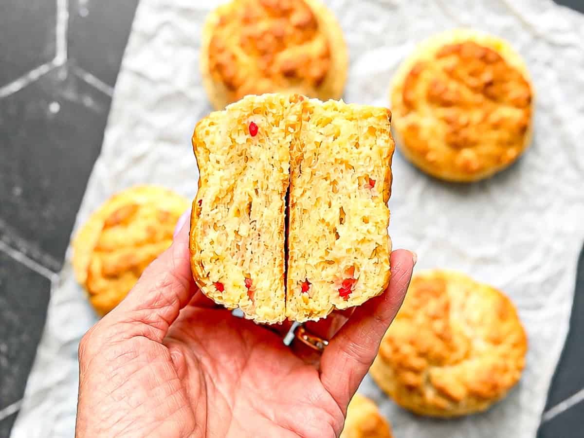 Author's hand holding a cut open pimento cheese biscuit.