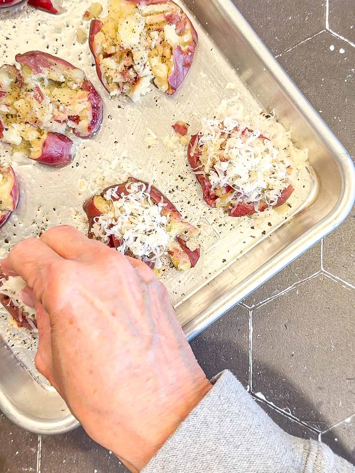 Sprinkling grated Parmesan cheese on top of potatoes before baking.