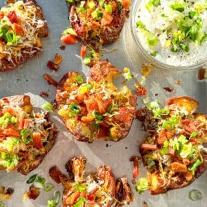 Close up of loaded breakfast smashed potatoes on a sheet pan.