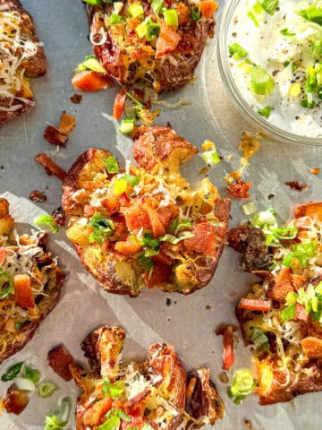 Close up of loaded breakfast smashed potatoes on a sheet pan.