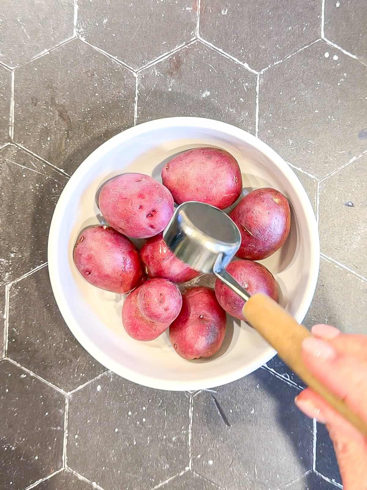 Adding water to a bowl of a small red potatoes.