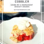 Pinterest image of a scoop full of strawberry cobbler on a white plate with a dollop of whipped cream.