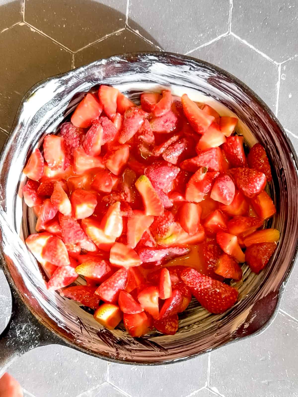 Strawberry cobbler filling in a buttered cast-iron pan.