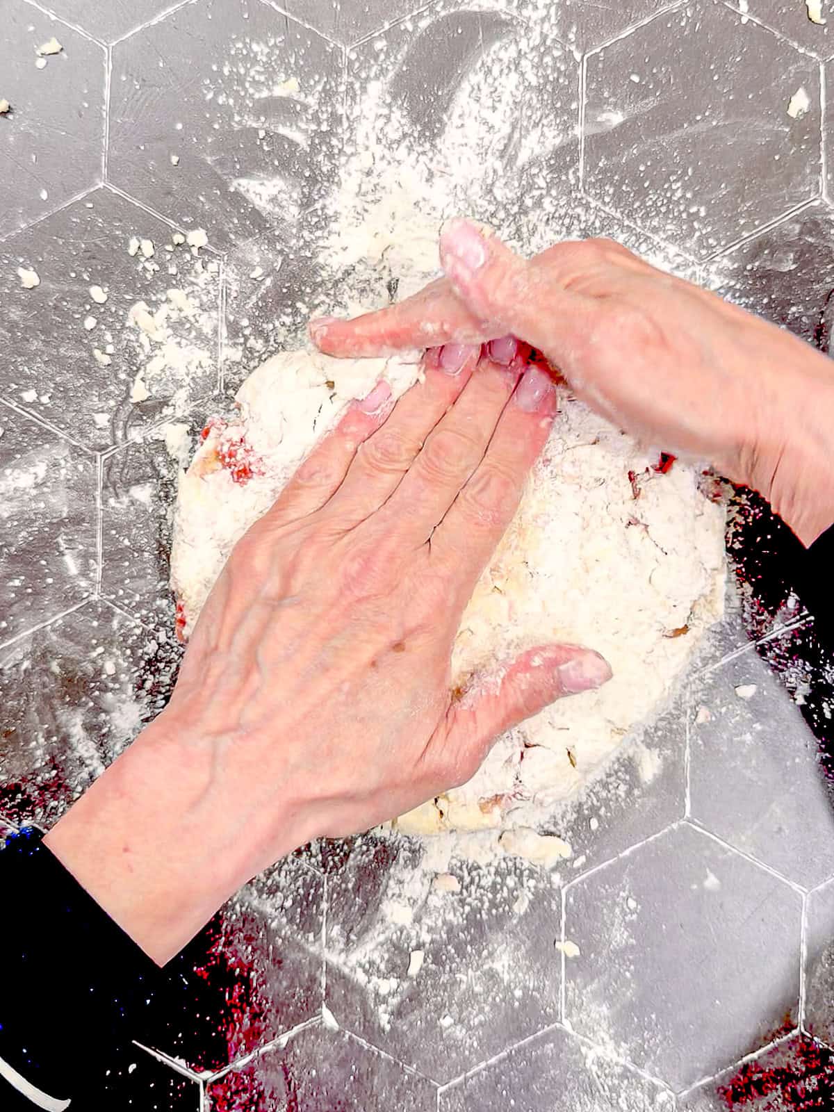 Using hands to shape scone dough into a circular shape about 1 inch thick.
