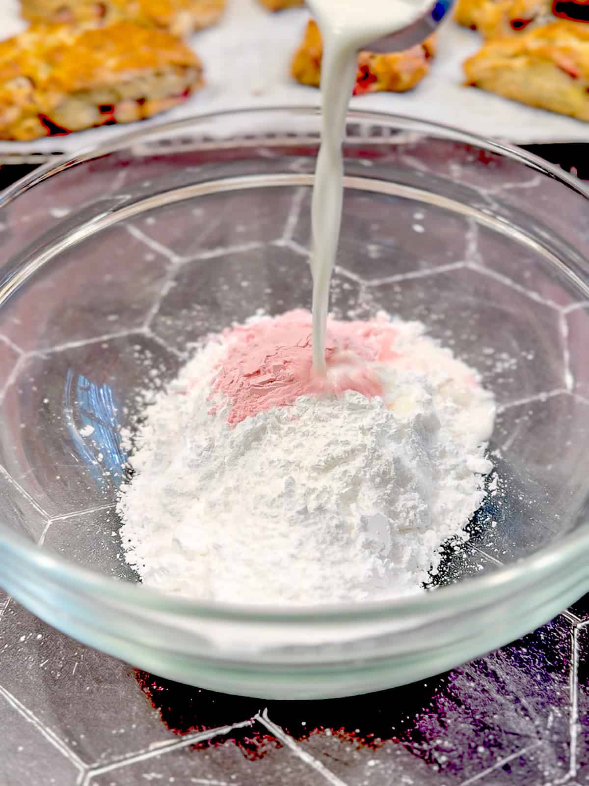 Powdered sugar, freeze dried strawberry powder, and milk in a glass bowl.