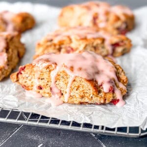 Glazed strawberry scones on a parchment paper covered wire rack.