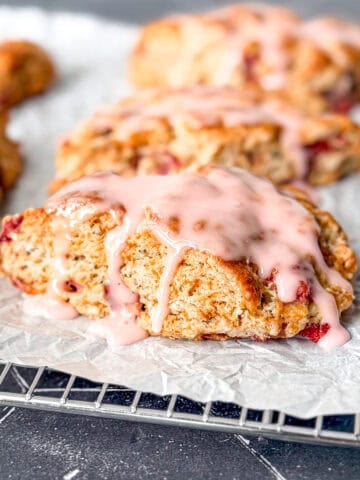 Glazed strawberry scones on a parchment paper covered wire rack.