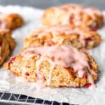 Glazed strawberry scones on a parchment paper covered wire rack.