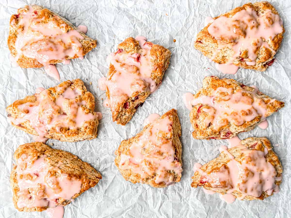 Glazed strawberry scones on parchment paper.