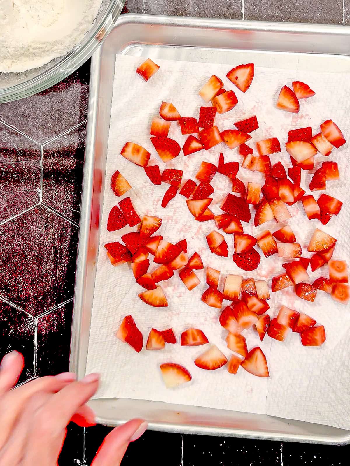 Diced strawberries on a paper towel lined sheet pan.