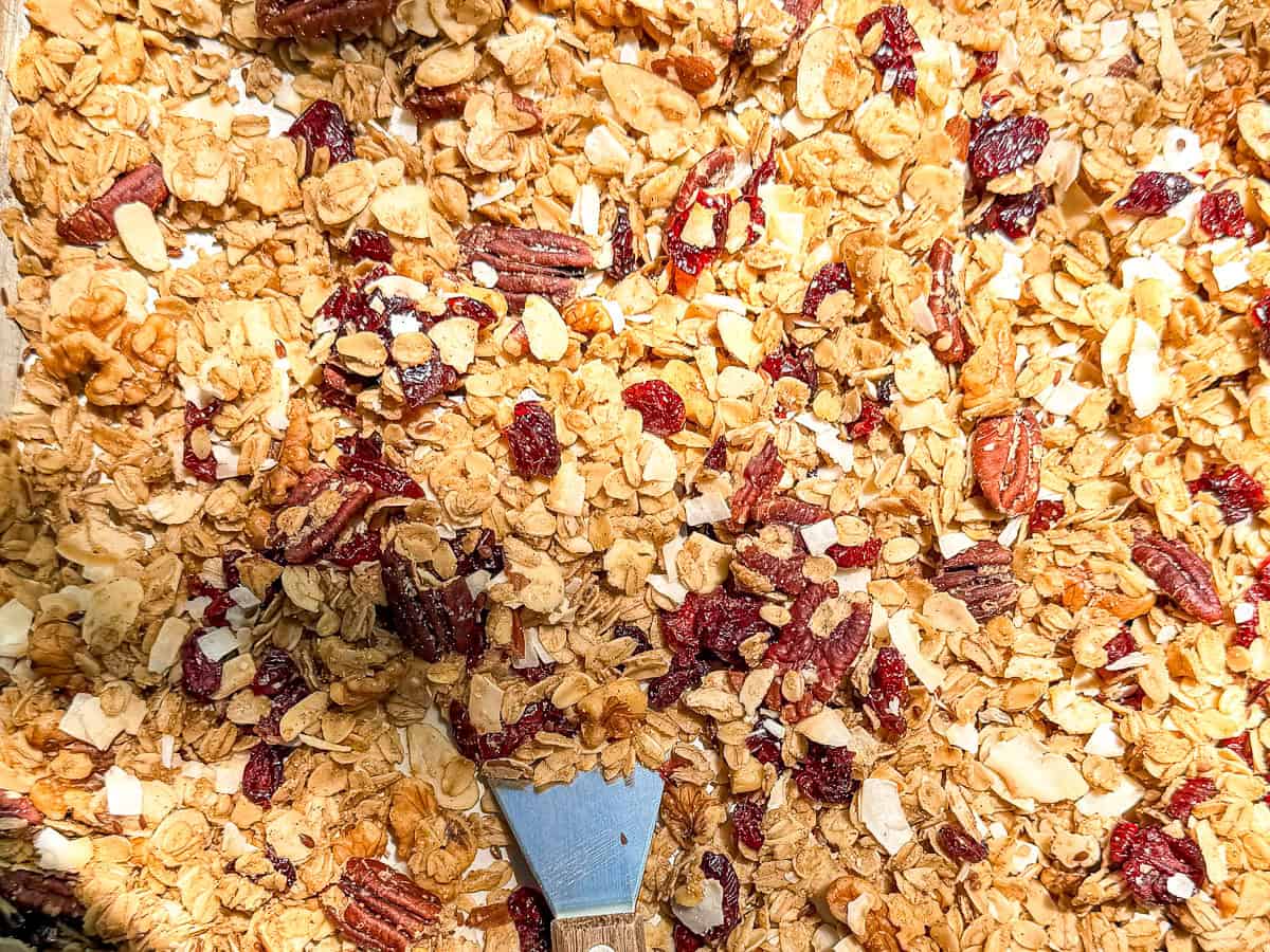Sheet pan of baked granola with a spatula in it.