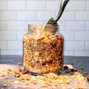 Jar of baked granola on a Black counter.