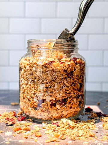 Jar of baked granola on a Black counter.