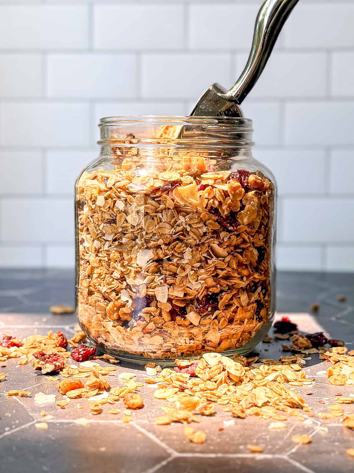 Jar of baked granola on a Black counter.