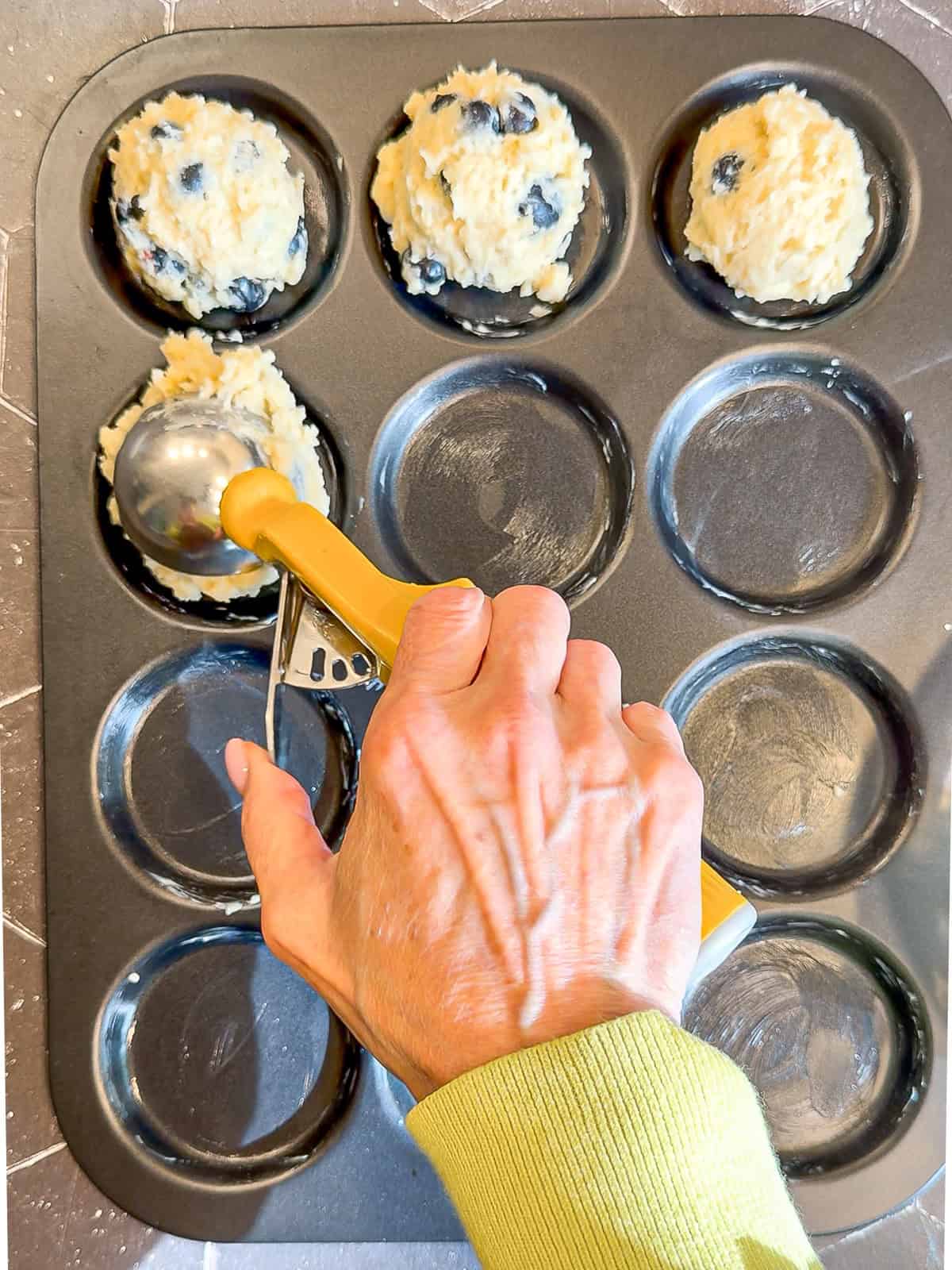 Scooping muffin batter into a muffin top pan.