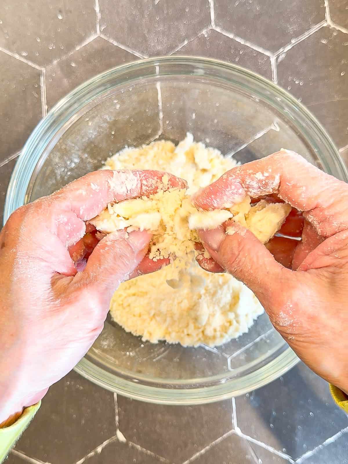 Using my fingers to make a crumb topping in a glass bowl.