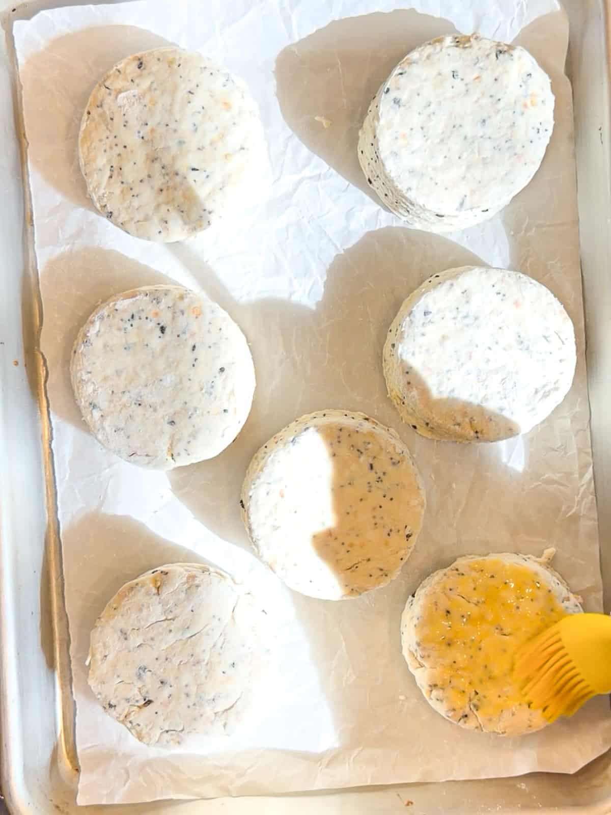 Brushing cream cheese biscuits with an egg wash.