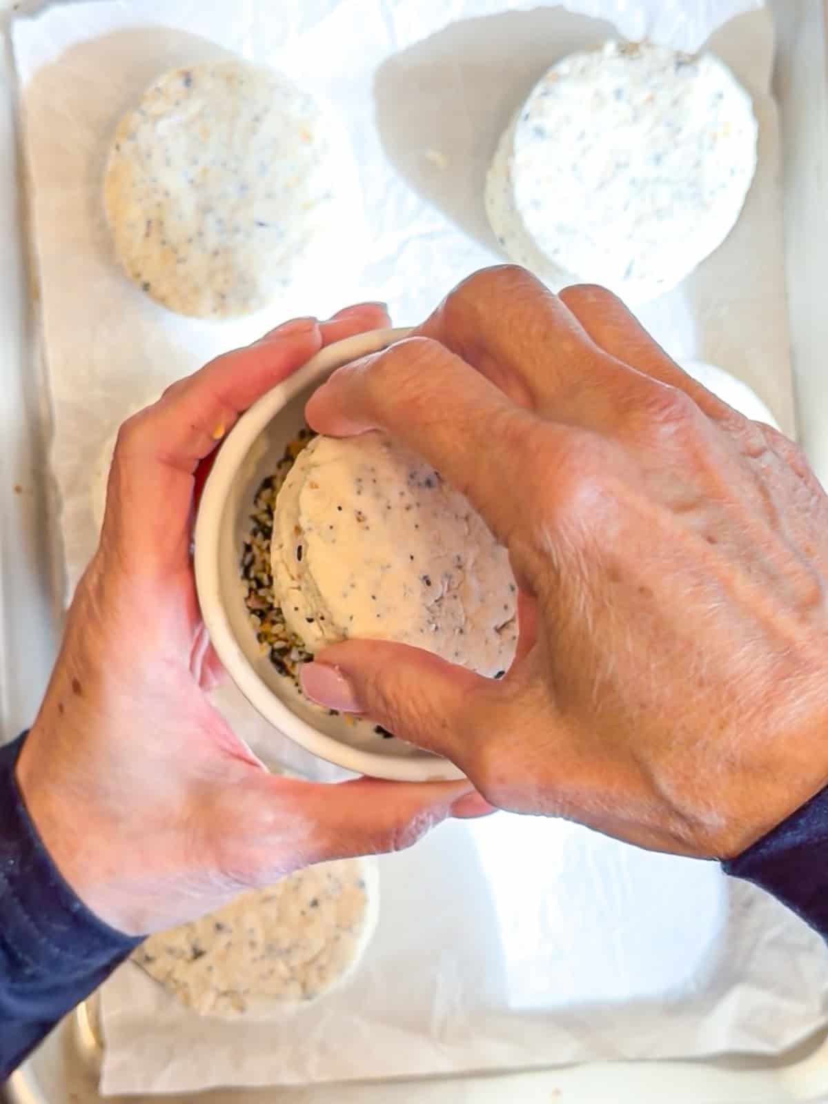 Pressing the top of a cream cheese biscuit into everything bagel seasoning.
