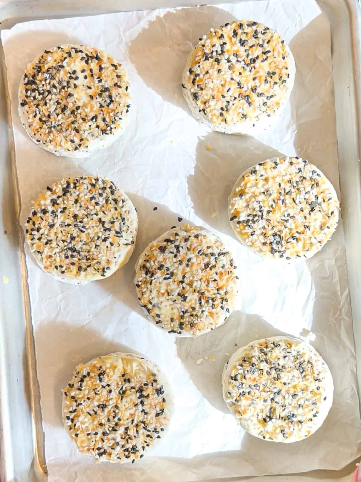 Cream cheese biscuits on a parchment paper lined sheet pan ready to bake.