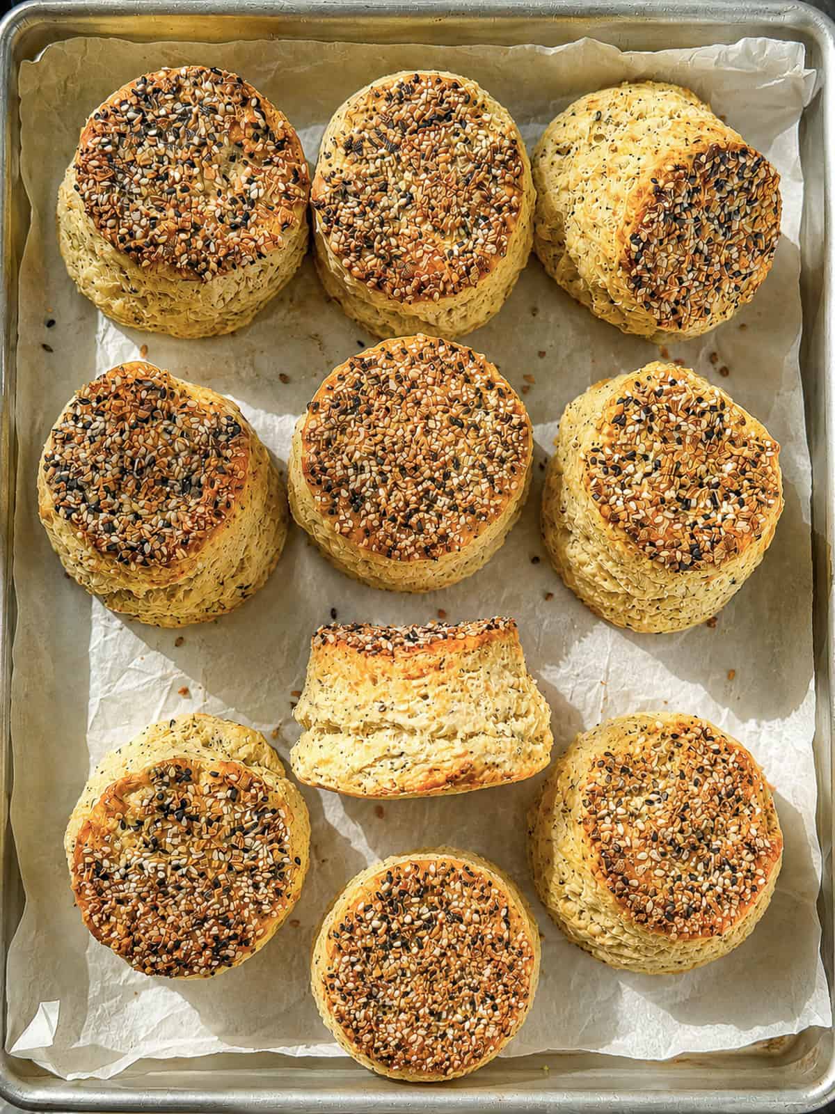 Cream cheese biscuits with everything seasoning on a parchment paper lined sheet pan.