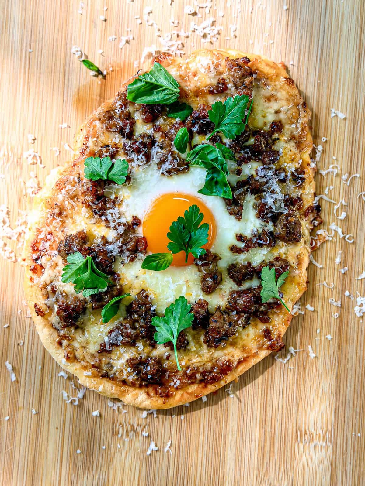 Flatbread breakfast pizza on a wooden cutting board.
