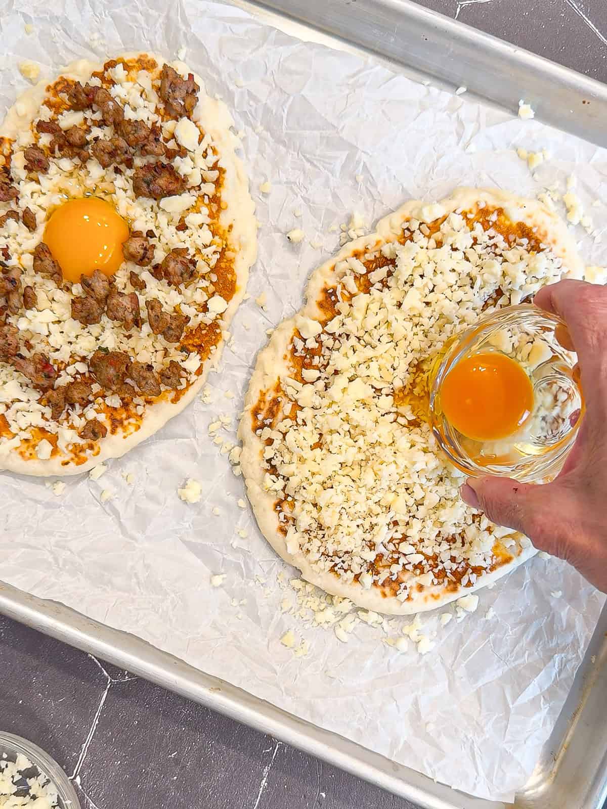 Adding an egg to the top of an unbaked flatbread pizza.