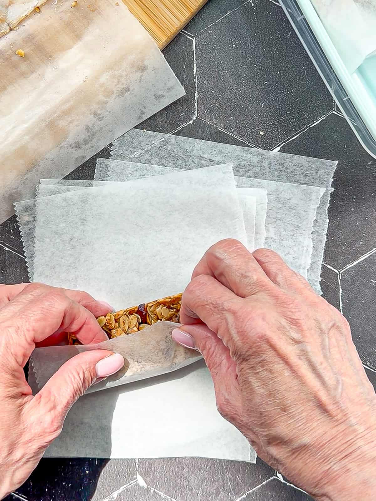 Rolling granola bars in paper.