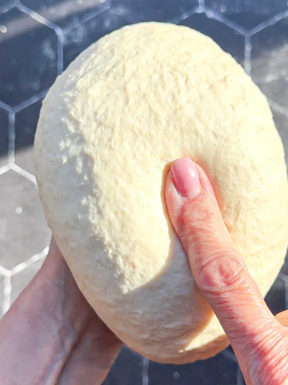 Pressing a finger into a ball of dough.