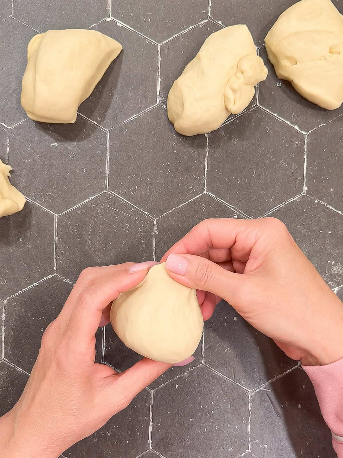 Pinching the top of a ball of dough with my fingers.
