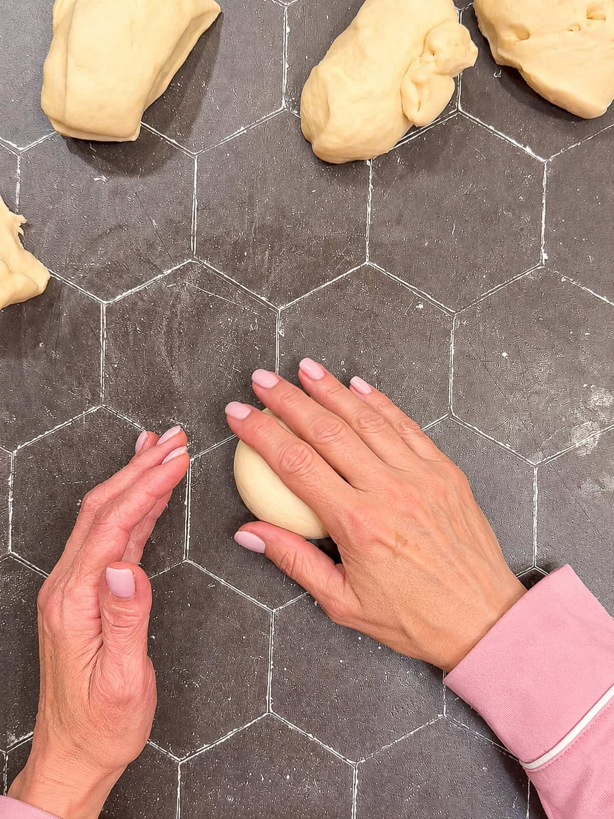 Rolling a ball of dough on a black counter.