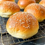 Hamburger buns on a wire rack.