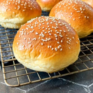 Hamburger buns on a wire rack.