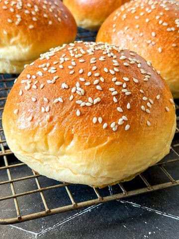 Hamburger buns on a wire rack.