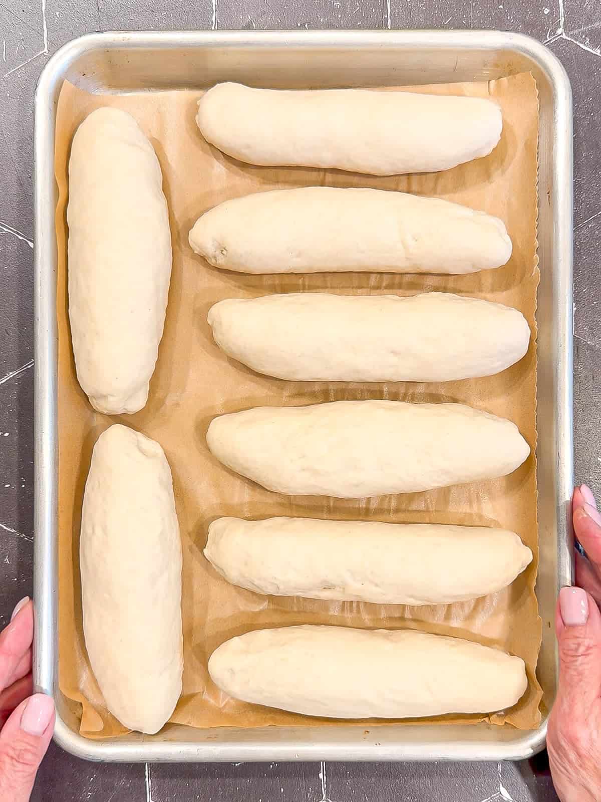 Hot dog buns on a sheet pan before rising.