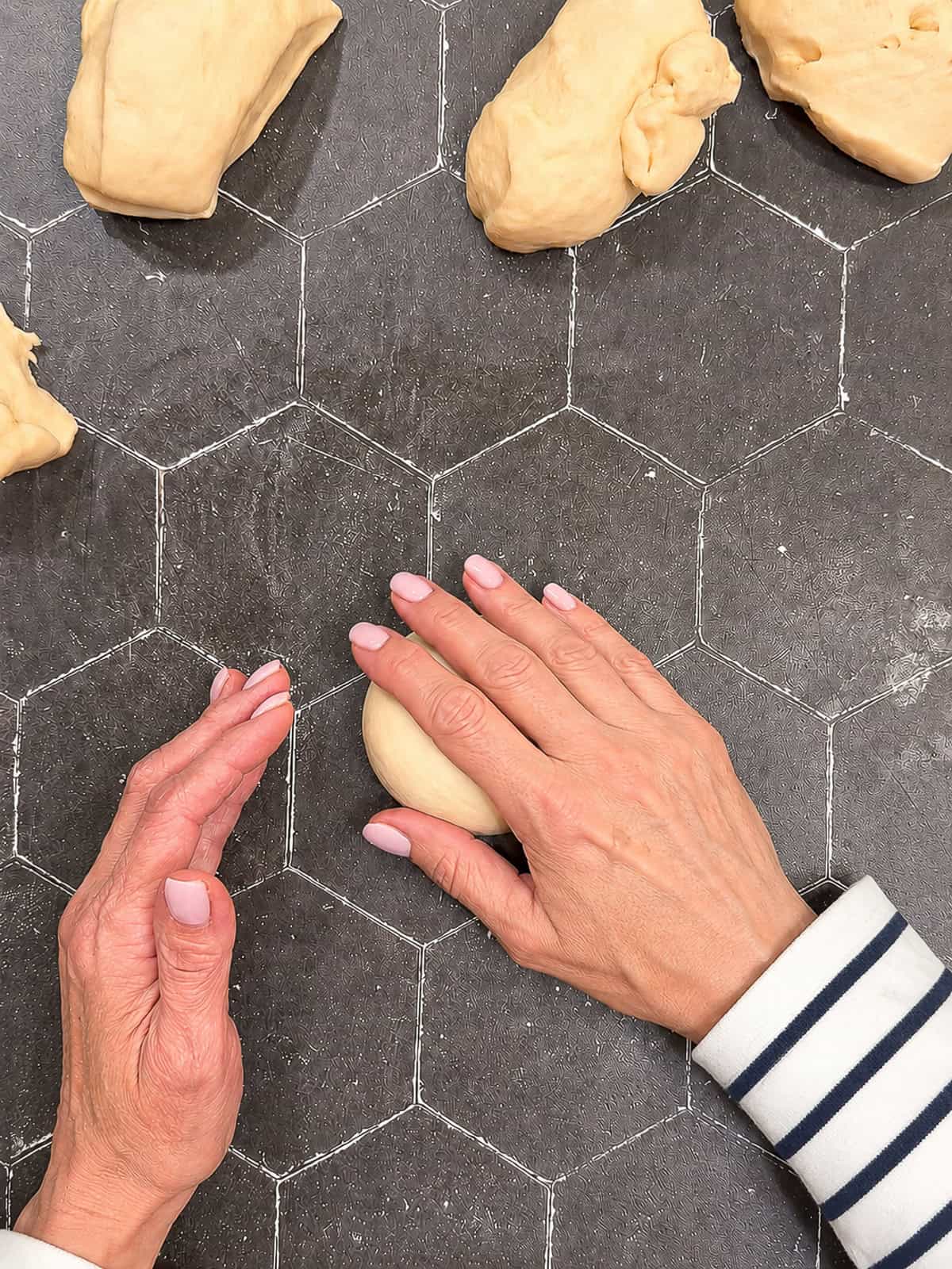 Rolling a ball of dough on a black counter.