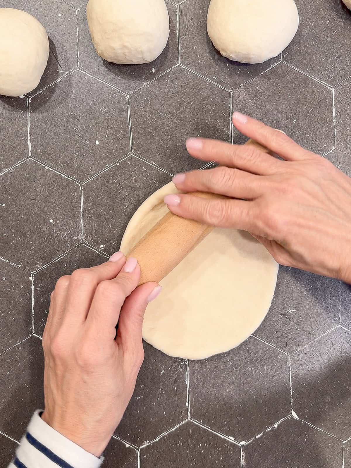 Rolling dough on a black counter.
