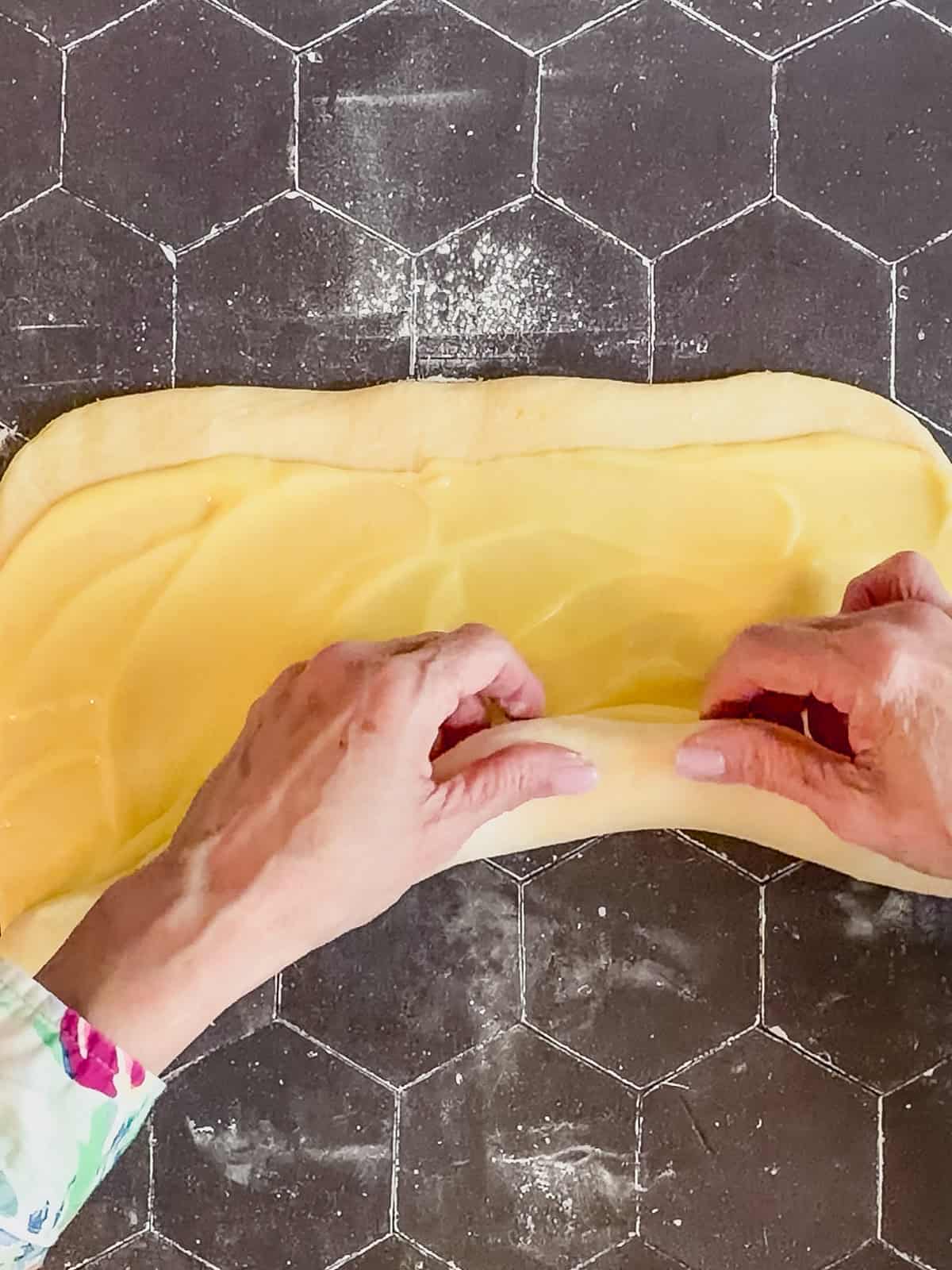 Rolling up a log of dough covered with lemon curd.