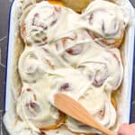 Swirling cream cheese frosting on top of lemon rolls.