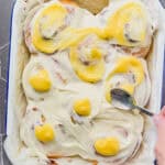 Swirling lemon curd into frosting on top of lemon rolls.