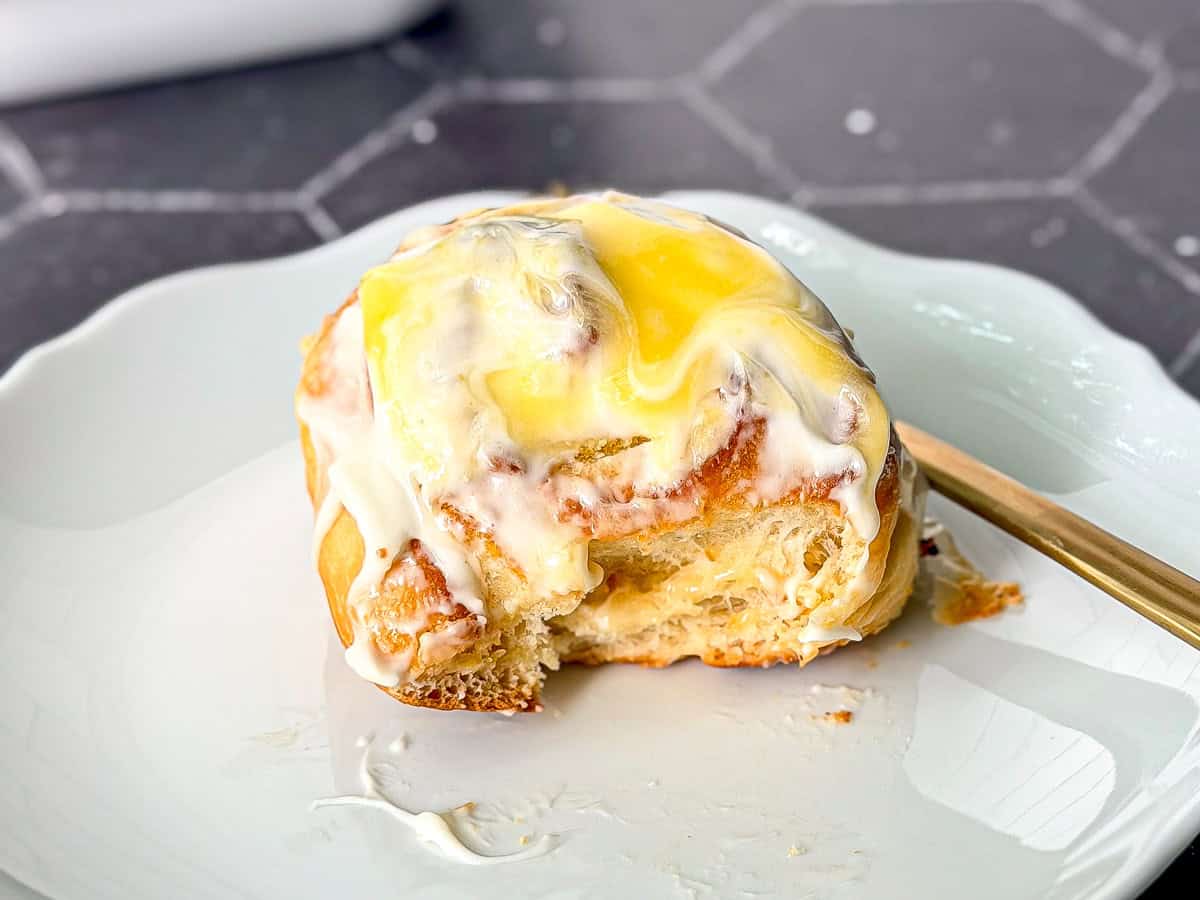 Side view of a lemon roll with cream cheese frosting and lemon curd on top