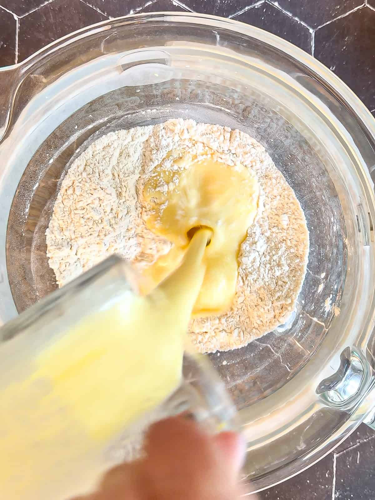 Pouring wet ingredients into dry ingredients to make brioche dough.