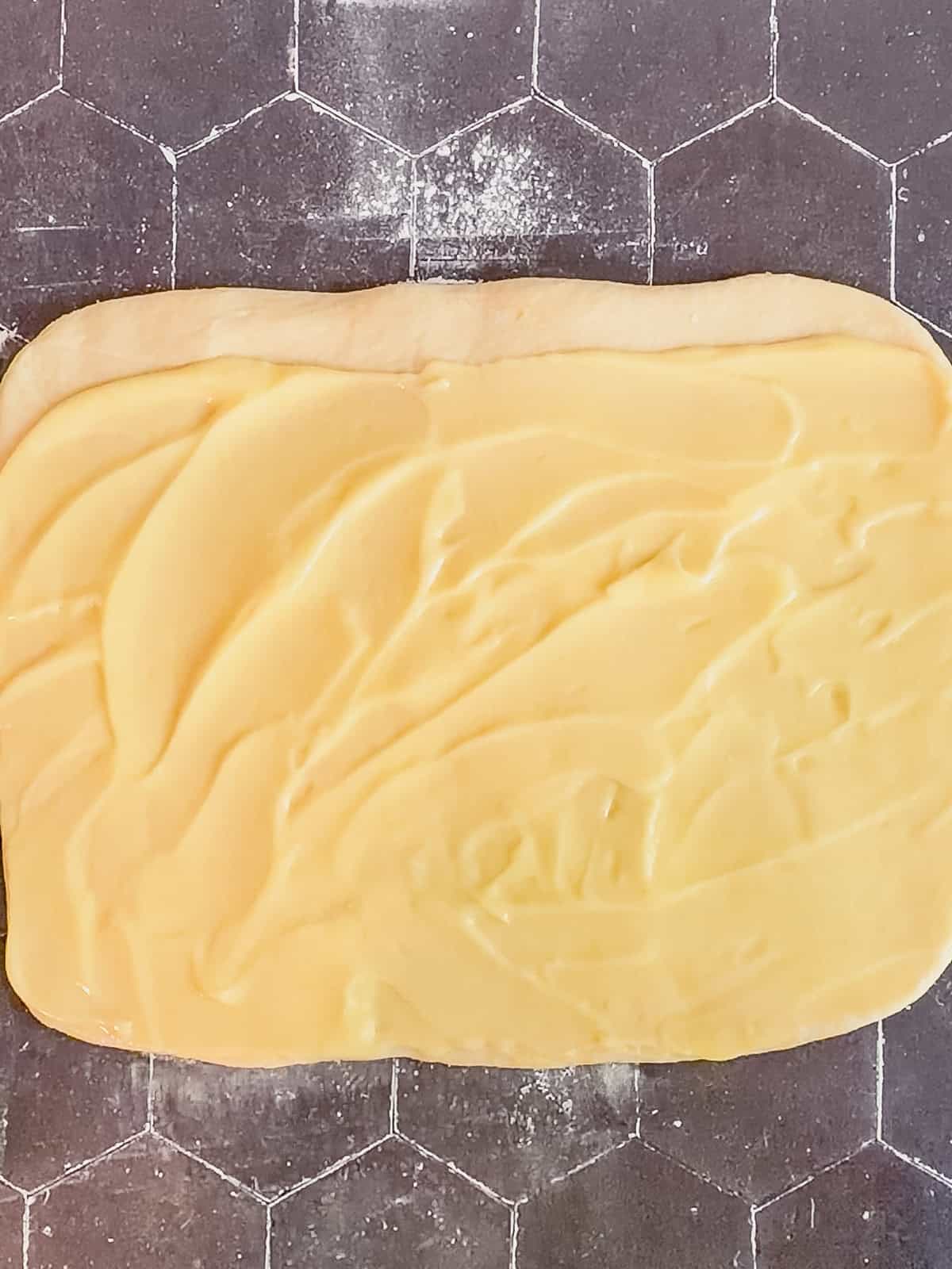 Lemon curd spread on a rectangular piece of brioche dough.