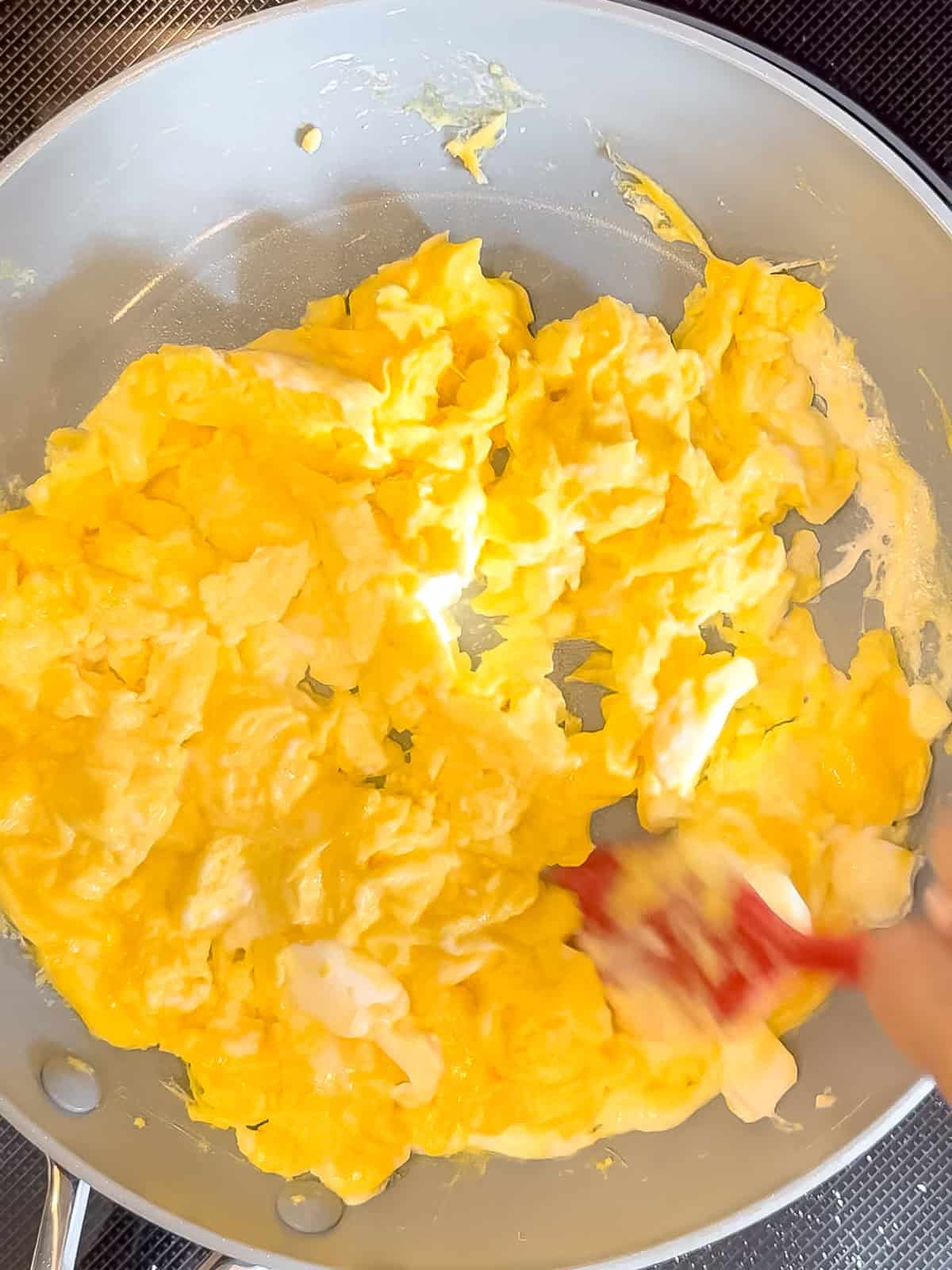 Folding dollop of mascarpone into cooked eggs.