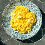 Creamy mascarpone scrambled eggs on a blue floral plate.
