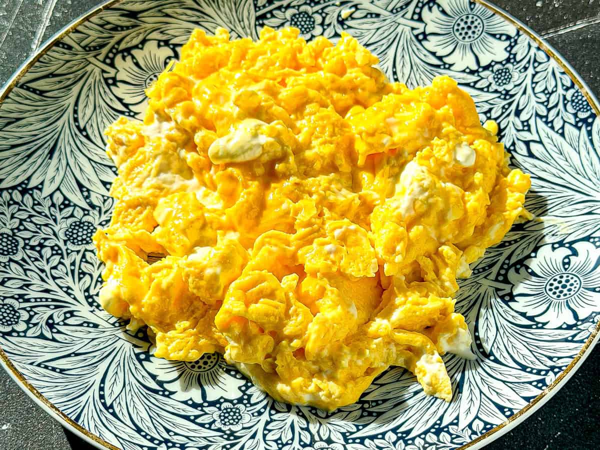 Creamy mascarpone scrambled eggs on a blue floral plate.