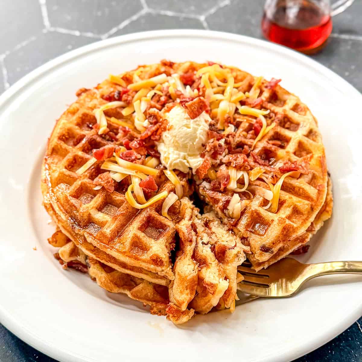 Bacon cheddar waffles with butter, cheddar, and bacon sprinkled on top.