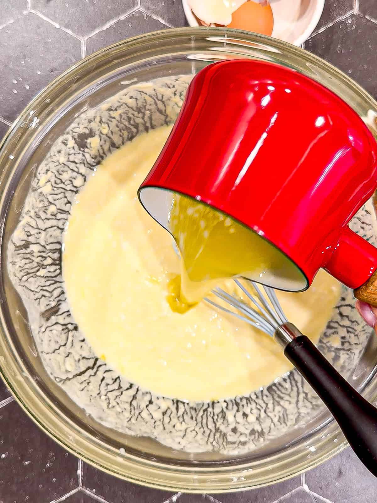 Pouring butter and oil into whisked buttermilk and eggs and vanilla.