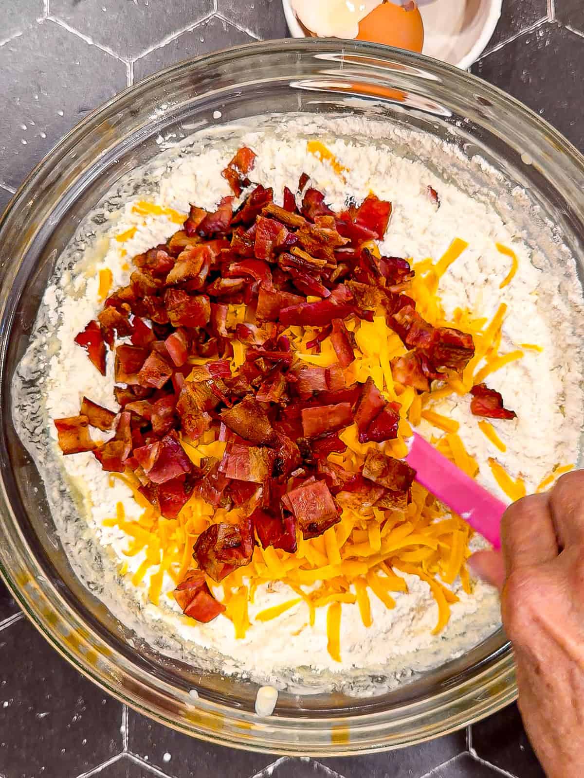 Mixing cheddar and bacon into waffle batter.