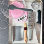 Biscuit baking tools on a sheet pan on a black tile background.
